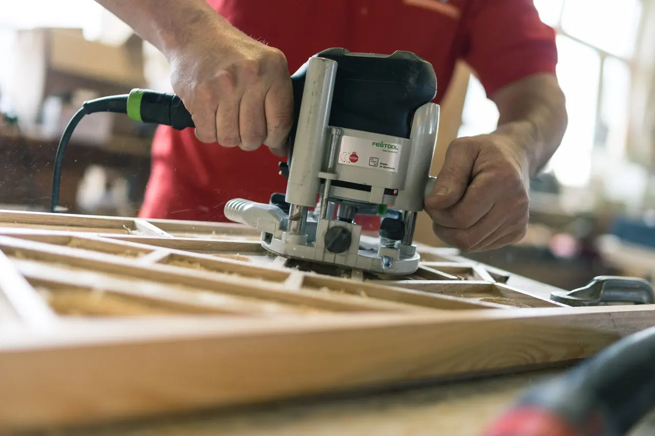 Schreiner bei der Arbeit mit der Oberfräse in der Werkstatt