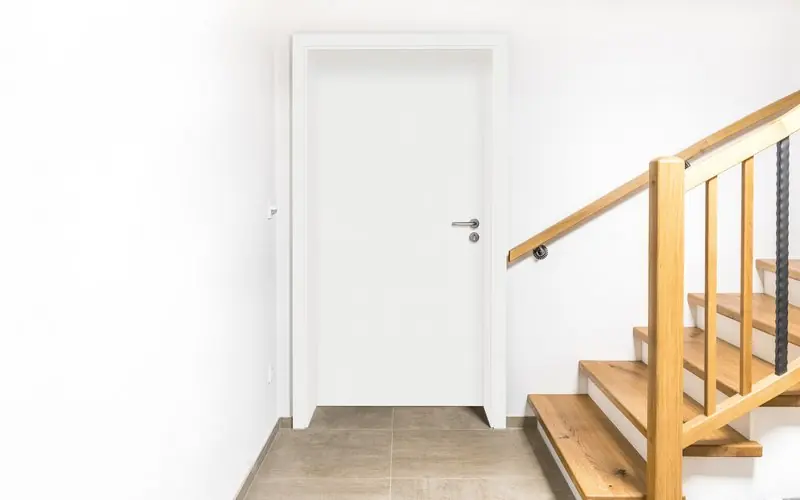 Weiße Innentür neben einer Holztreppe
